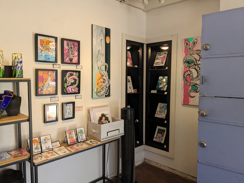 A corner of a room with colorful paintings and collages displayed on the walls.